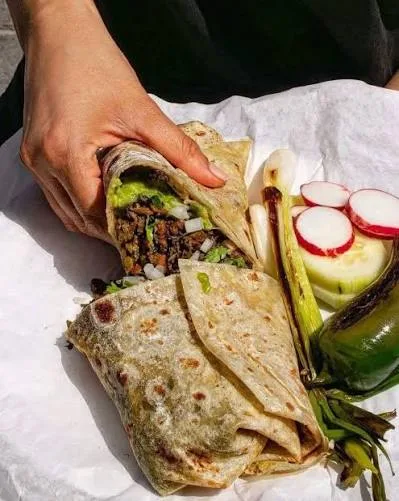 Carne asada burrito cut in half with grilled vegetables